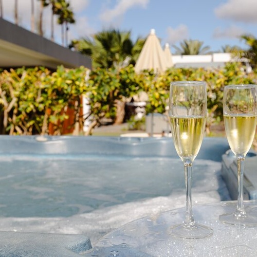 Dos copas de champán junto a jacuzzi, experiencia de lujo en 001 Hotels Corporativa.