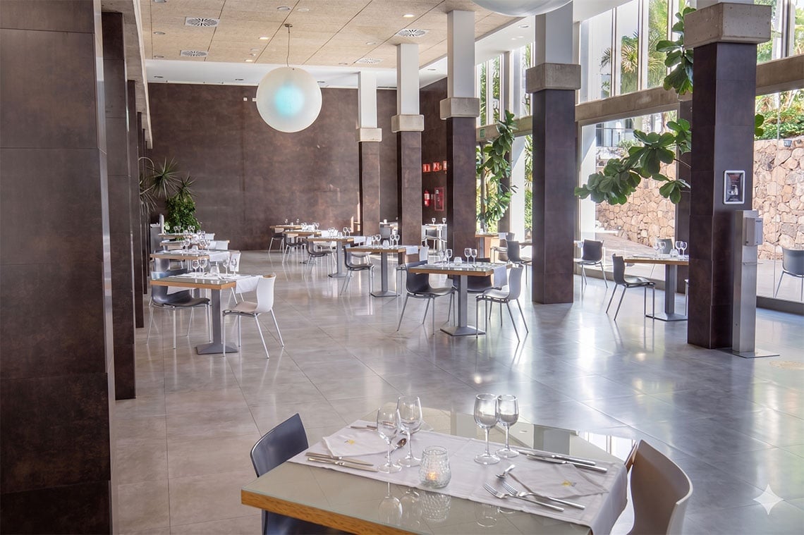 Restaurant de l'hôtel 001 Bahía Playa : tables dressées, vues sur jardin.