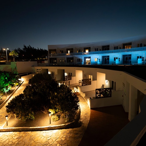 Vista nocturna del hotel 001 Hotels: Corporativa con iluminación ambiental y vegetación.
