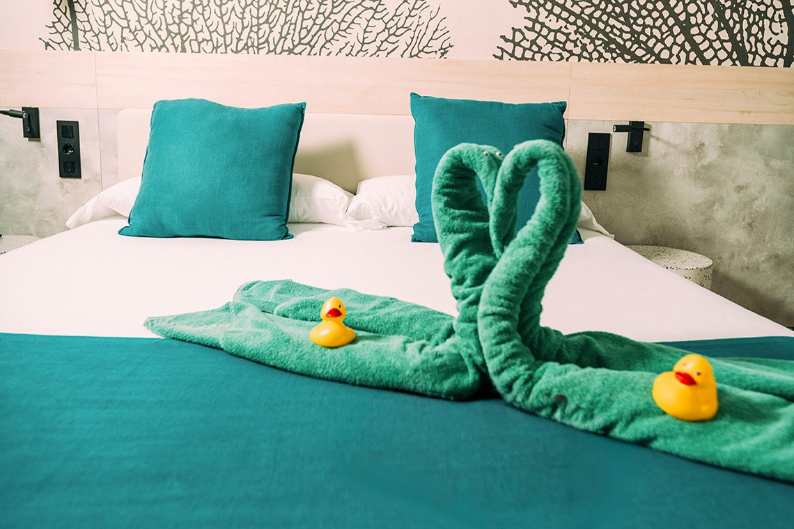Bett im 001 Higos Beach Hotel: Handtuch-Schwan und Quietscheentchen.