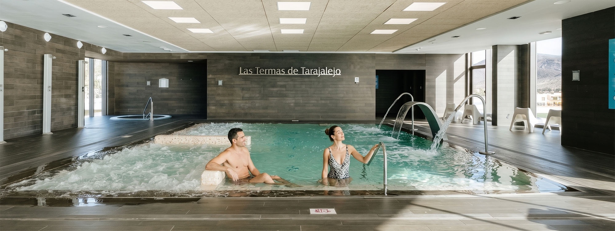 001 Hotels: Corporativa - Couple enjoys a hydrotherapy pool at a modern spa.