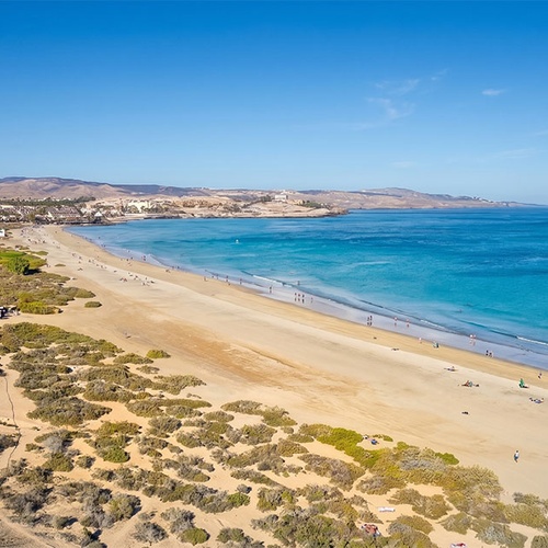 001 Hotels: Corporativa. Vista aérea de playa con mar azul y edificios en la costa.