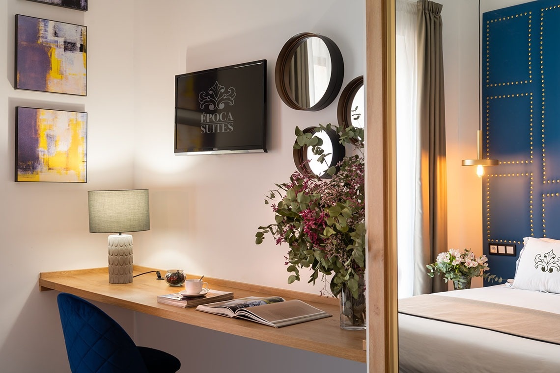 una habitación con un escritorio y una televisión que dice epoca suites