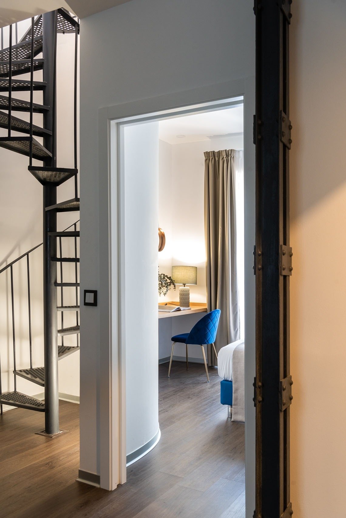una escalera de caracol conduce a una habitación con una cama y un escritorio