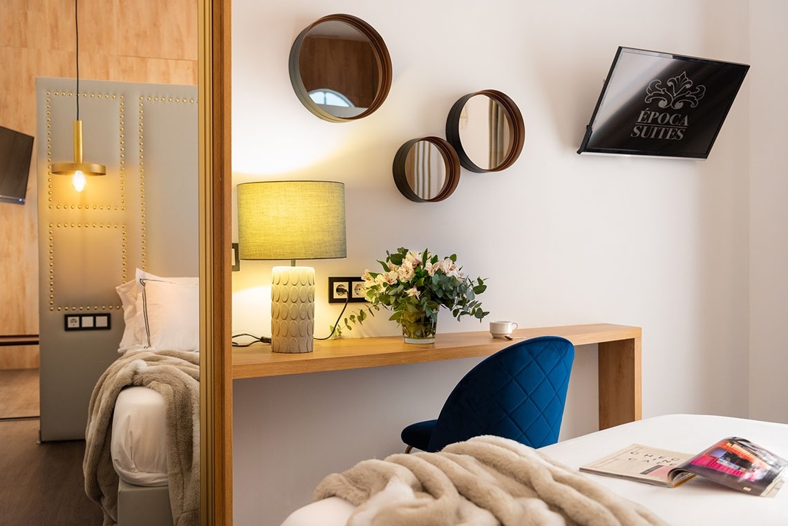 una habitación con una mesa y una televisión que dice epoca suites