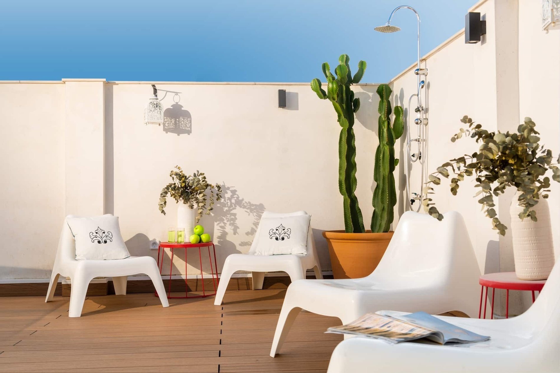 un patio con sillas blancas y un cactus en una maceta