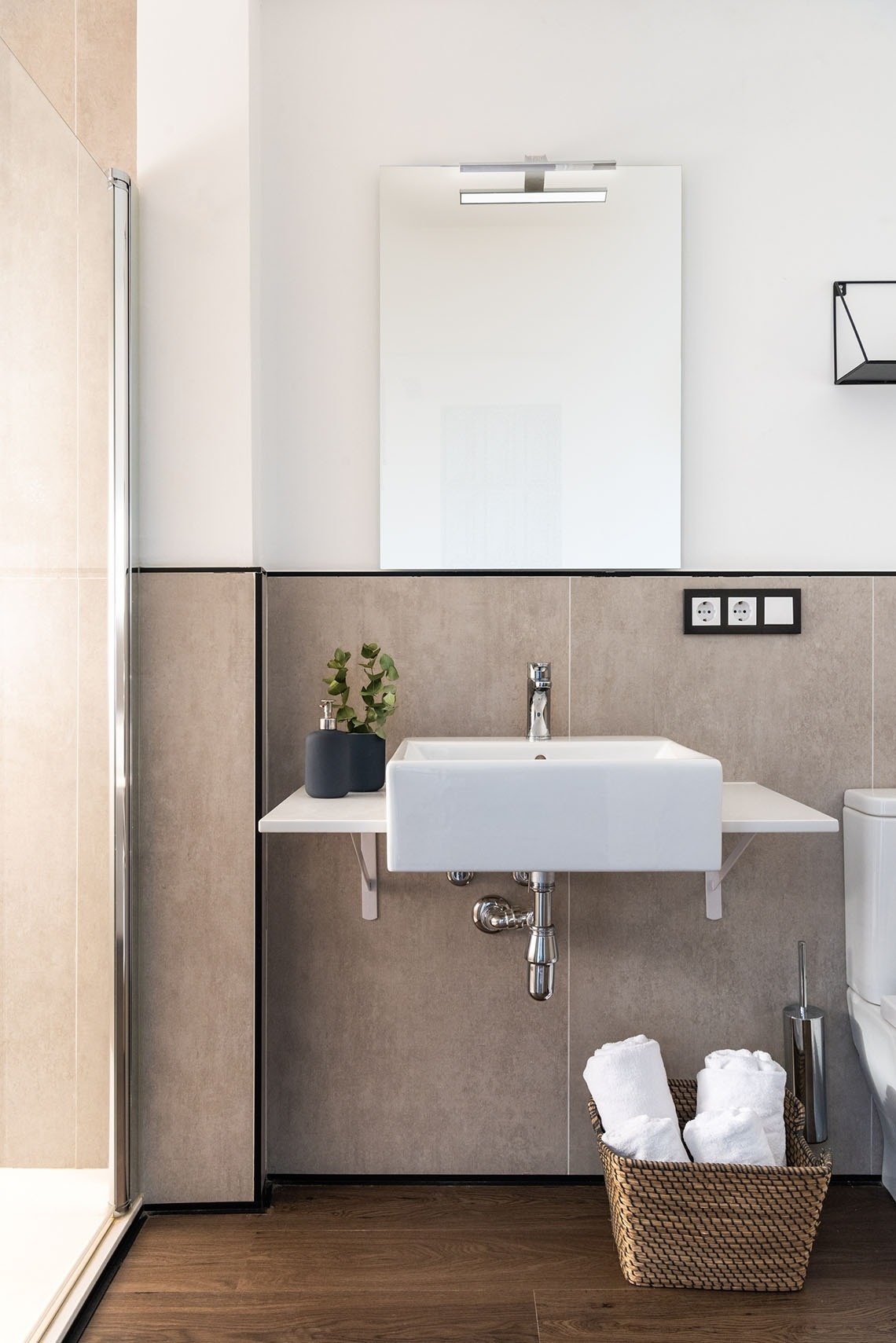 un baño con lavabo y espejo y una canasta de toallas