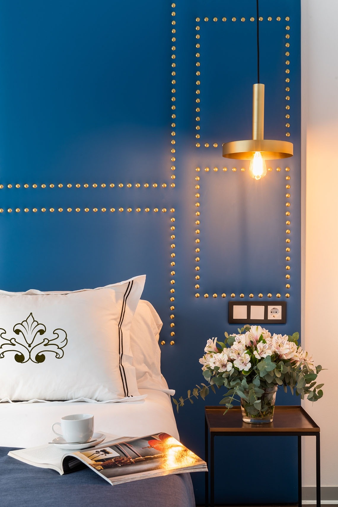 una cama con una almohada blanca y un jarrón de flores