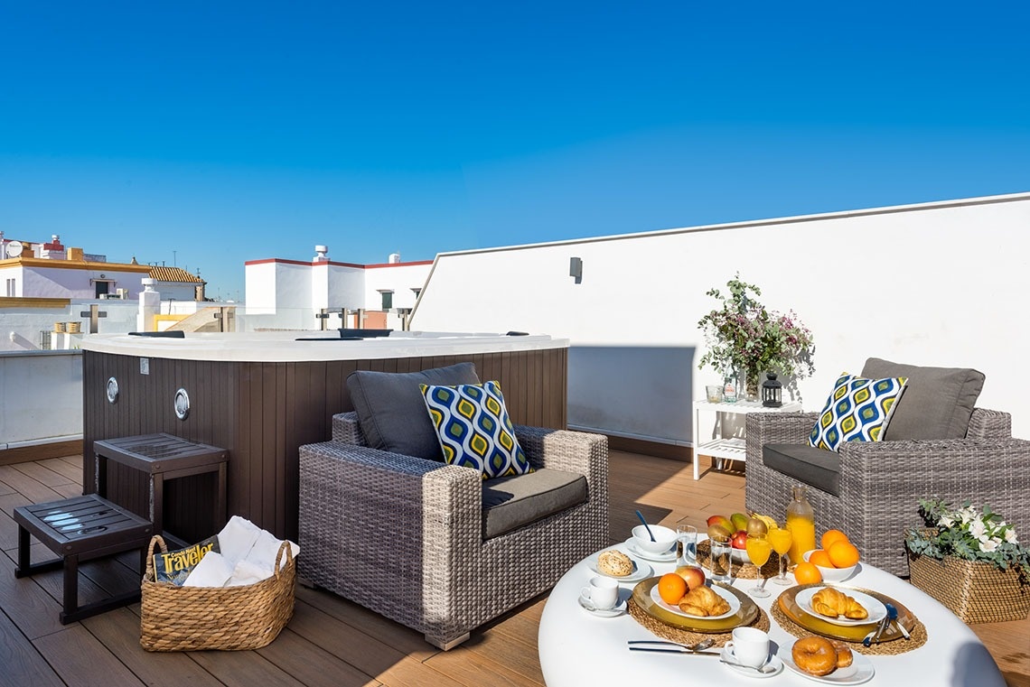 un jacuzzi en una terraza con sillas y una mesa de desayuno