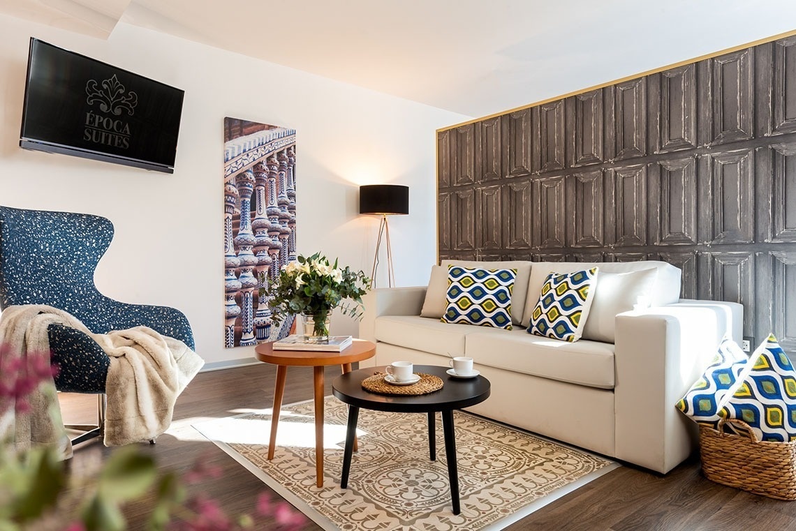 una sala de estar con un sofá y una televisión que dice epoca de suites