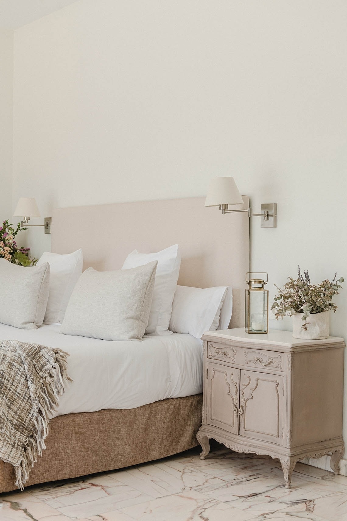 a bedroom with a bed and a nightstand with a vase of flowers on it