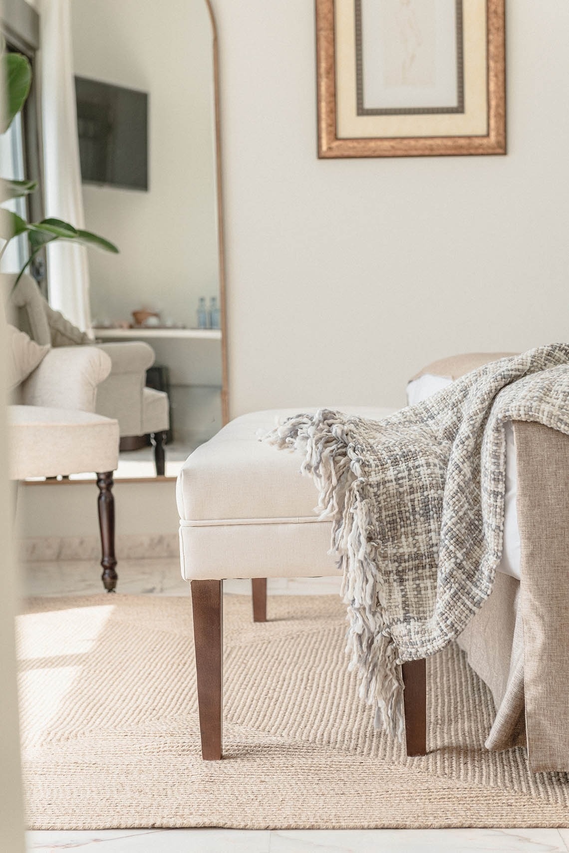 a bedroom with a bench and a blanket on the bed