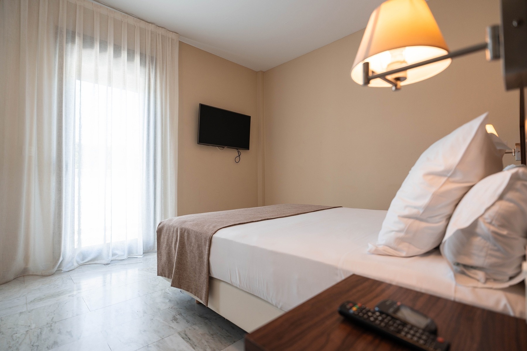 a hotel room with a bed and a television on the wall