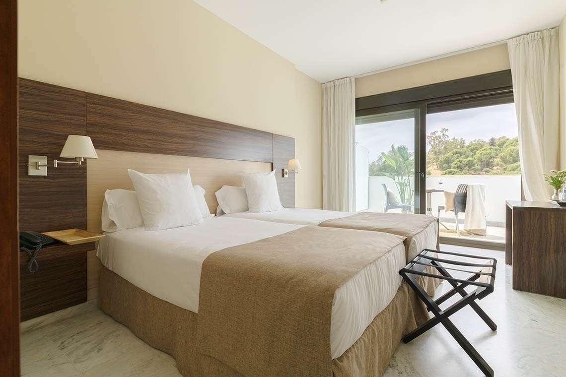 a hotel room with two beds and a sliding glass door