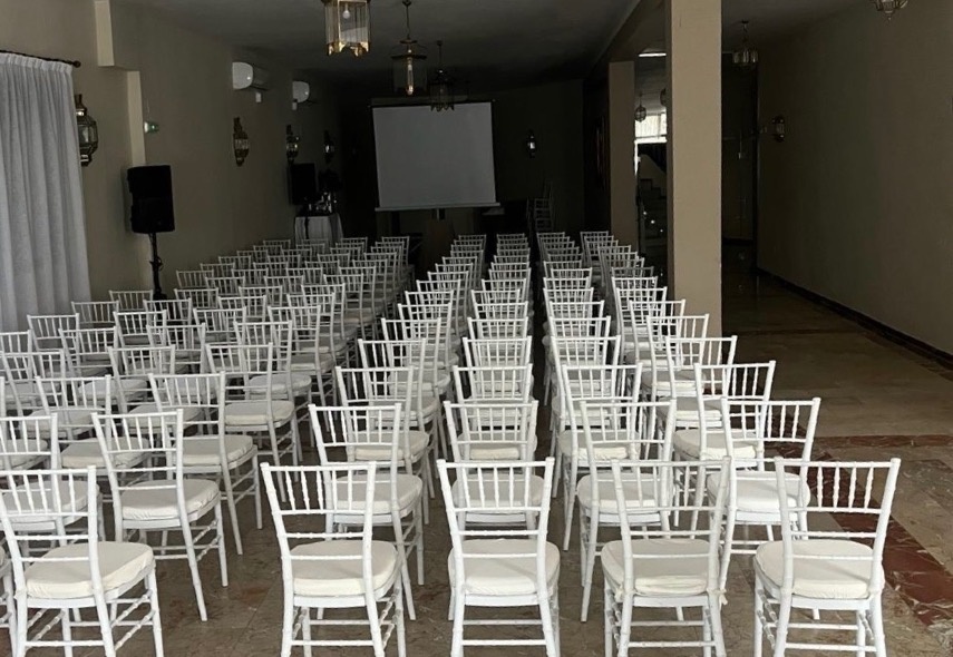 una sala llena de sillas blancas y una pantalla