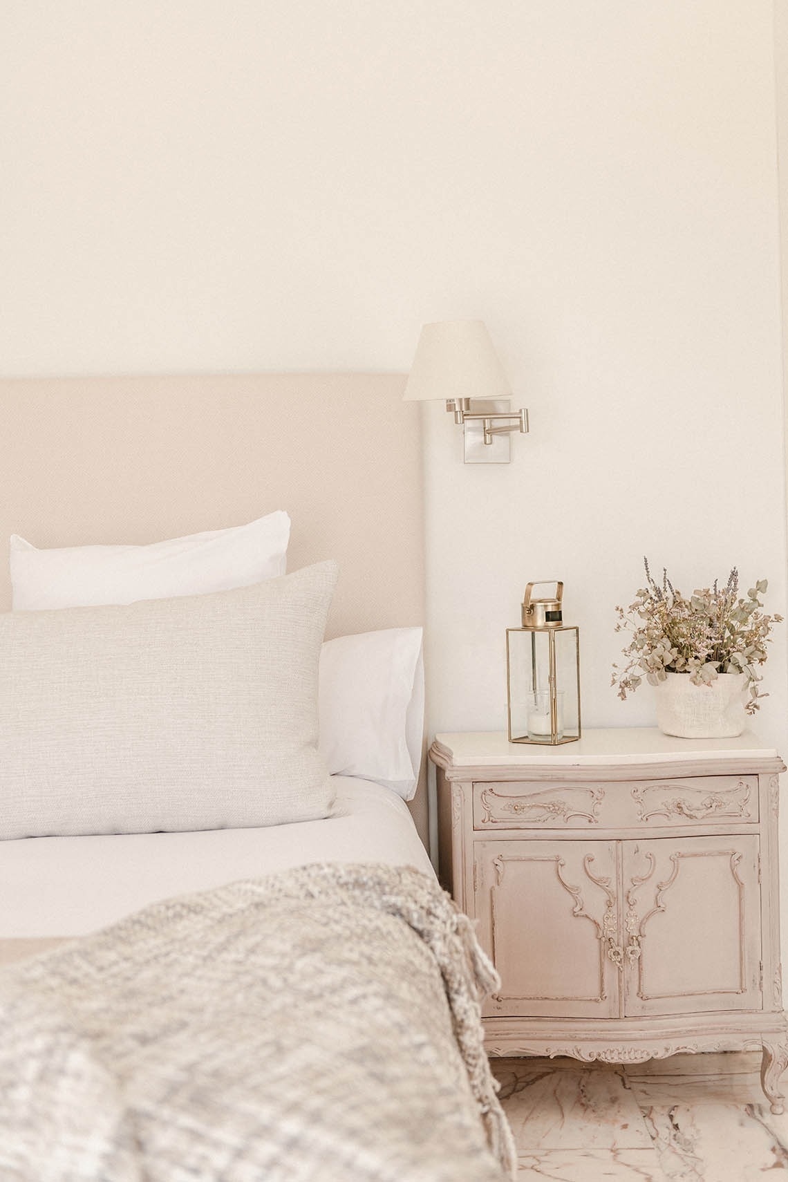a bedroom with a bed and a nightstand with a vase of flowers on it