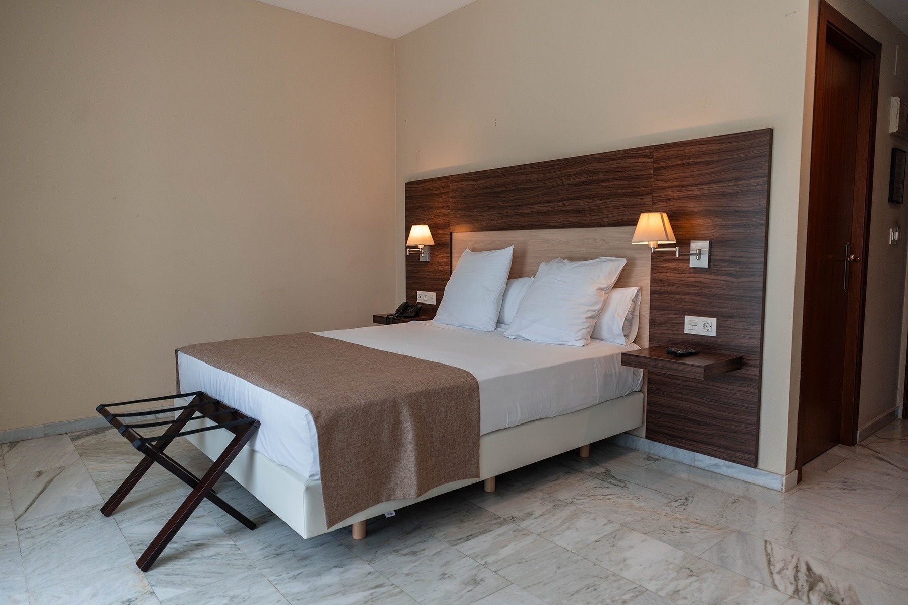 a hotel room with a white bed and a brown blanket