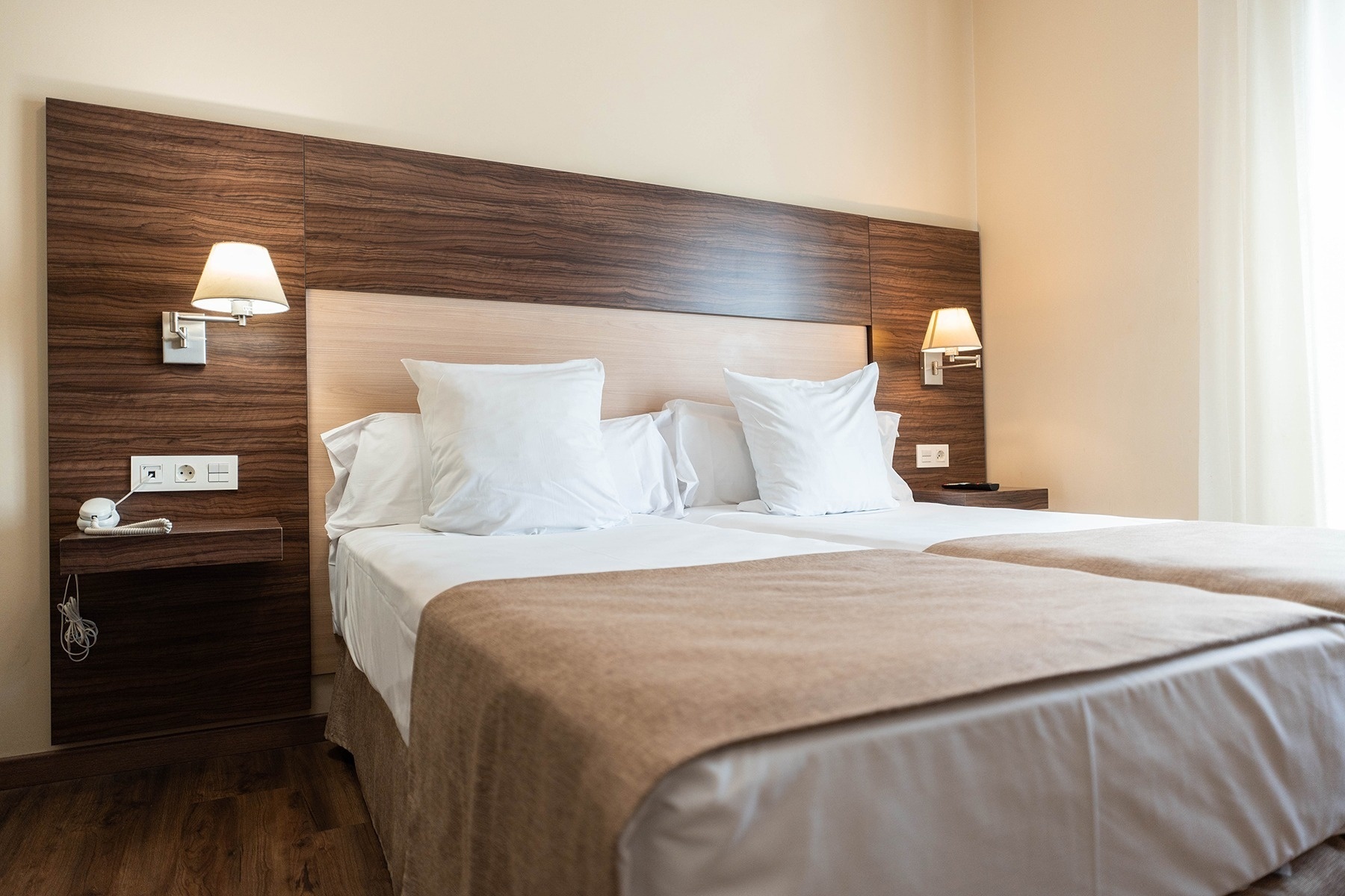 a hotel room with two beds and a wooden headboard