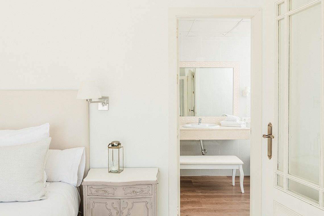 a bedroom with a nightstand and a bathroom with a sink