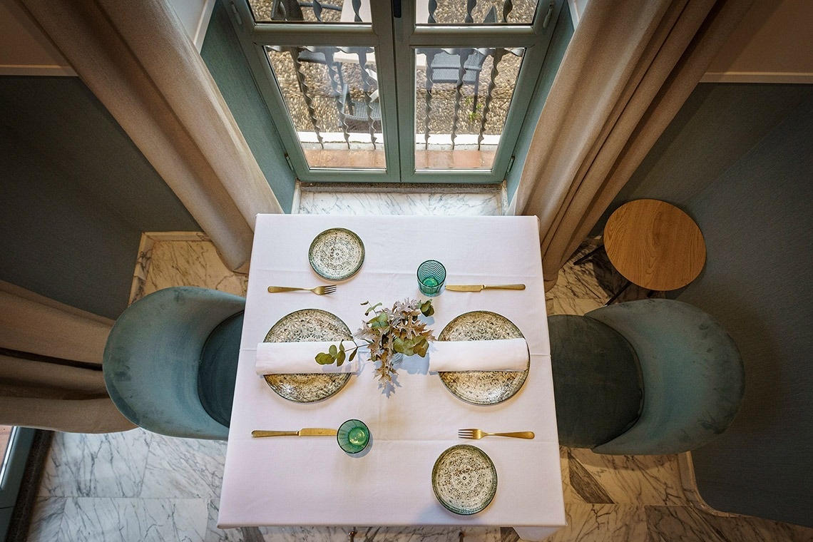 a table with plates and utensils on it in front of a window