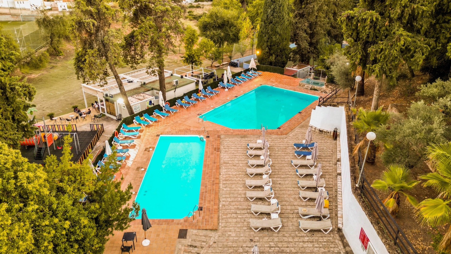 an aerial view of a swimming pool surrounded by chairs and umbrellas