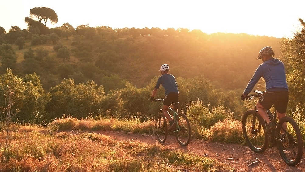 two people are riding bicycles down a dirt road