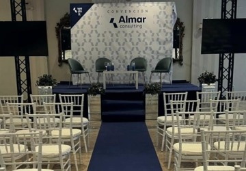 rows of white chairs are lined up in a room with a blue carpet that says ' almar ' on it