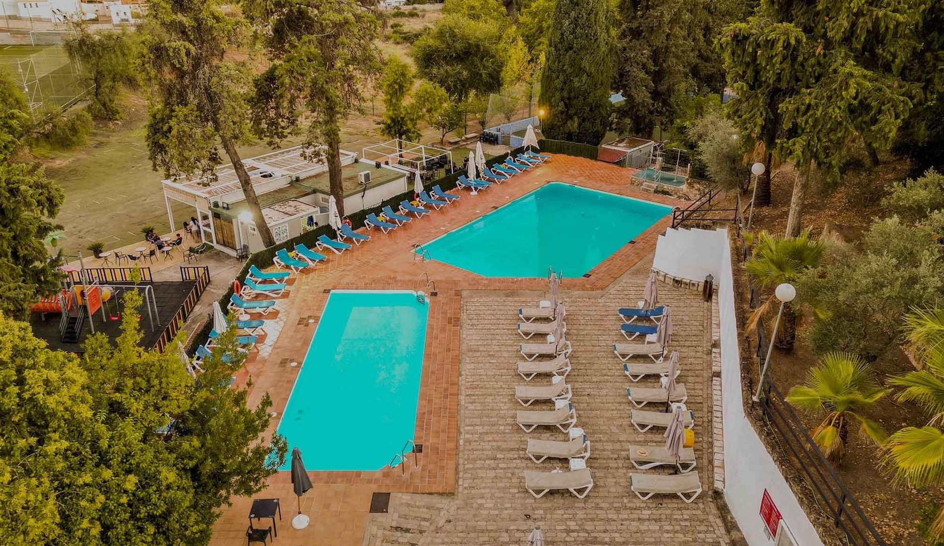 una vista aérea de una piscina rodeada de sillas y árboles