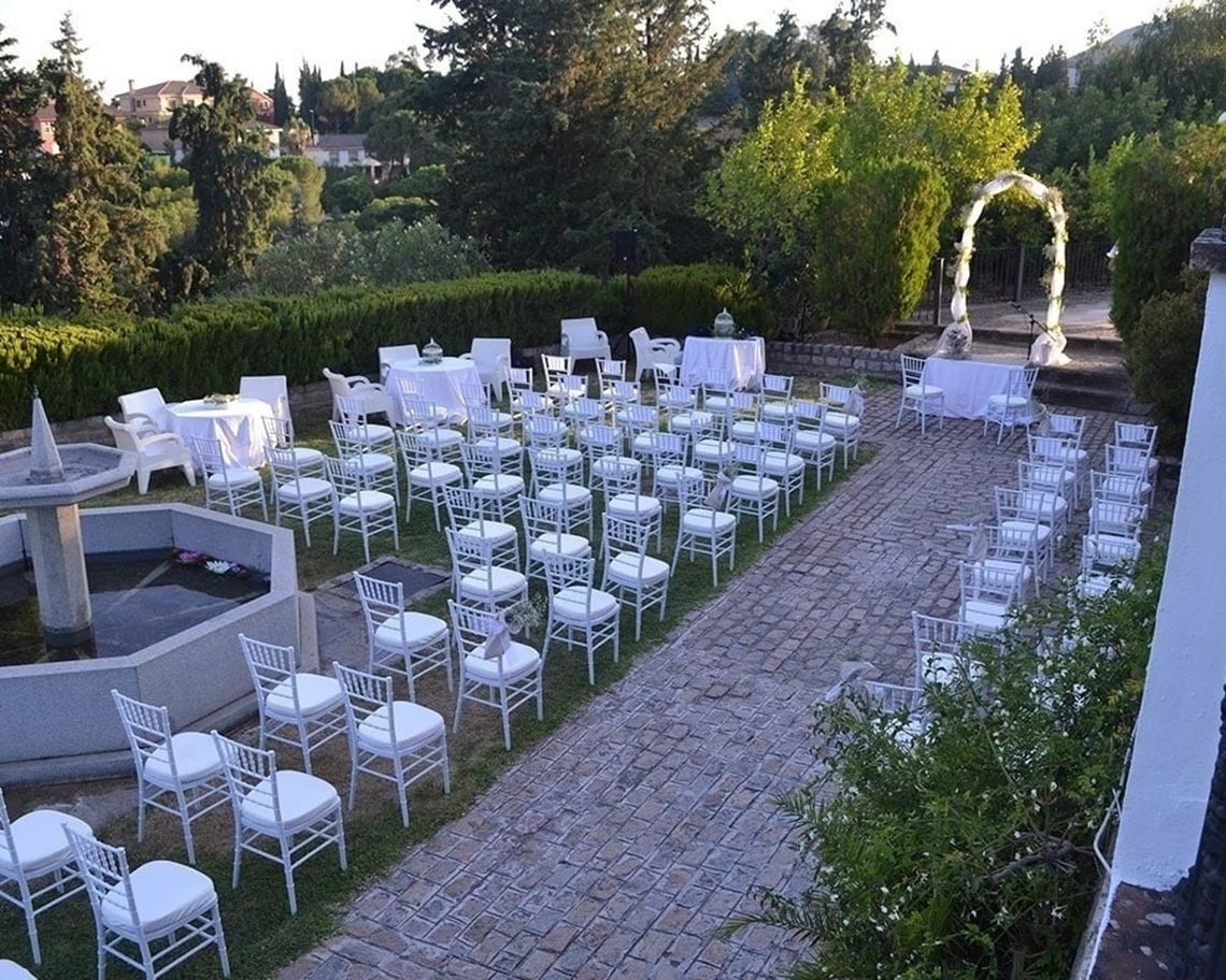 una fila de sillas blancas están dispuestas para una ceremonia de boda