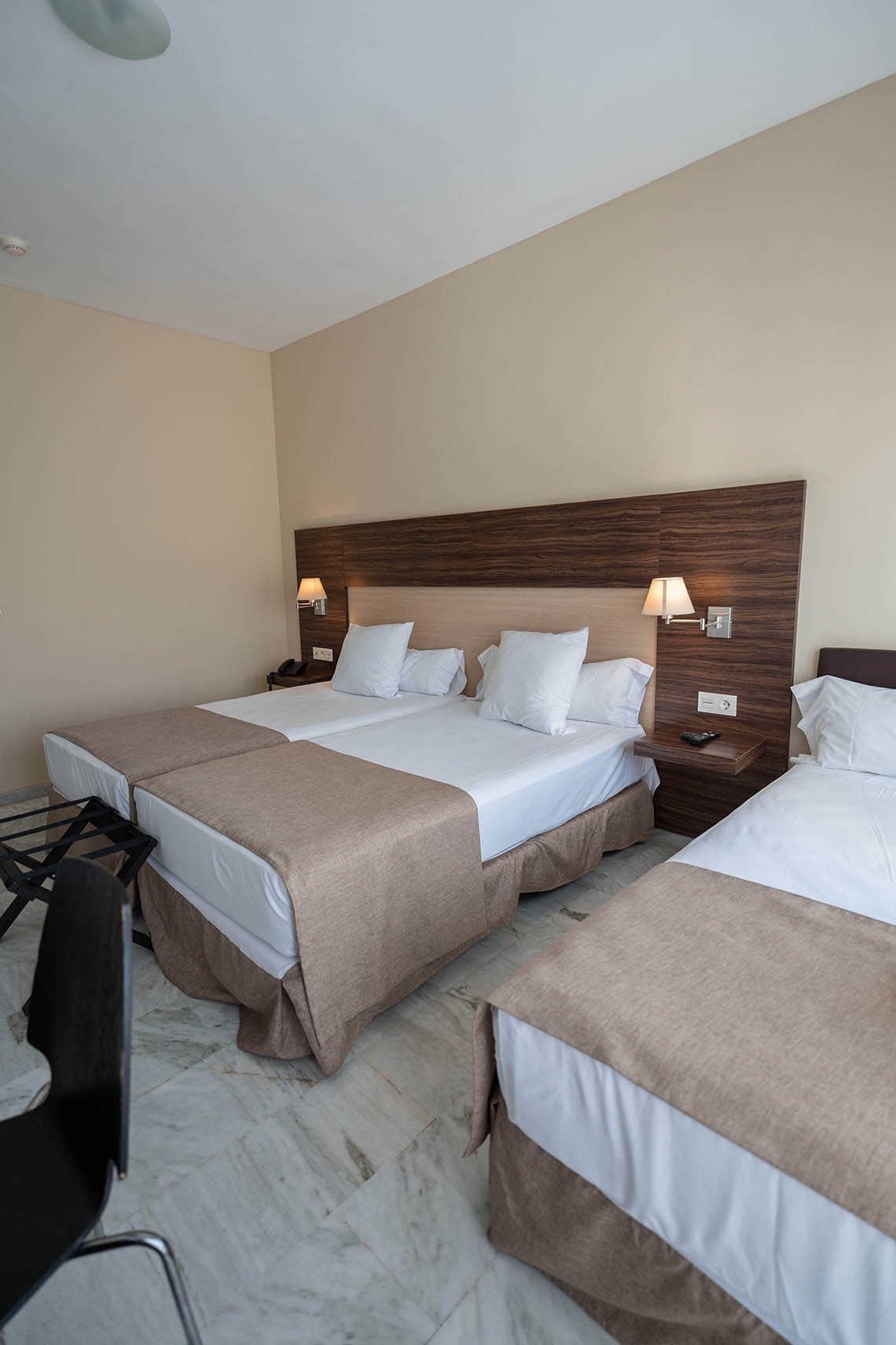 a hotel room with three beds and a chair