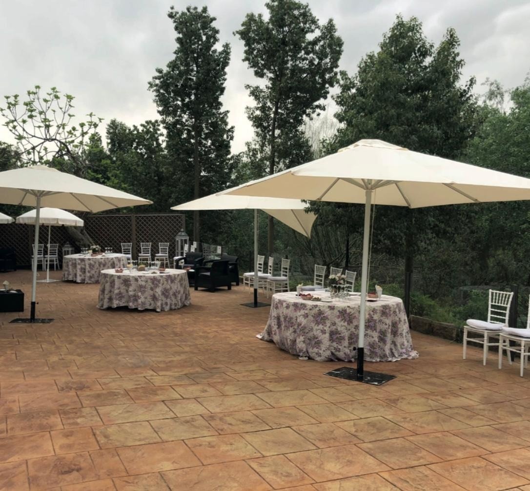 un patio con mesas y sillas y paraguas en un día nublado
