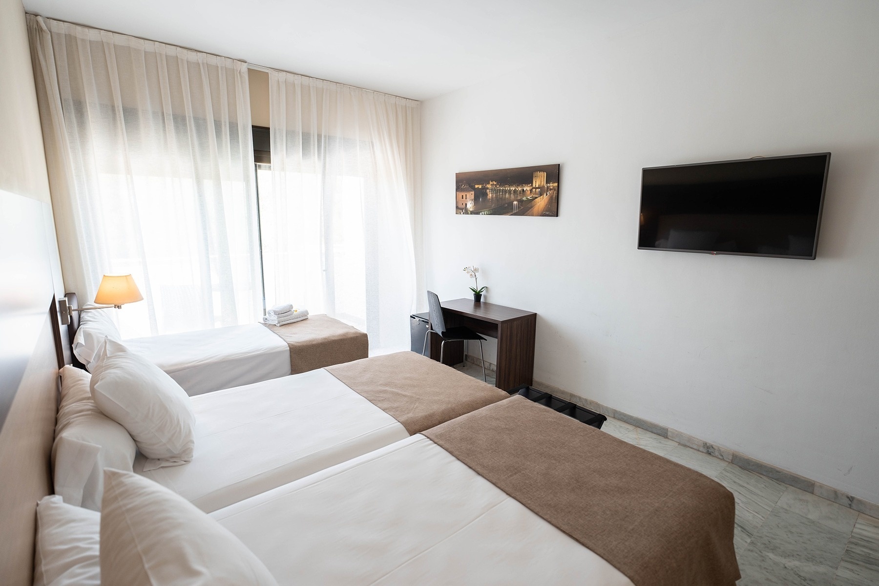 a hotel room with two beds and a flat screen tv