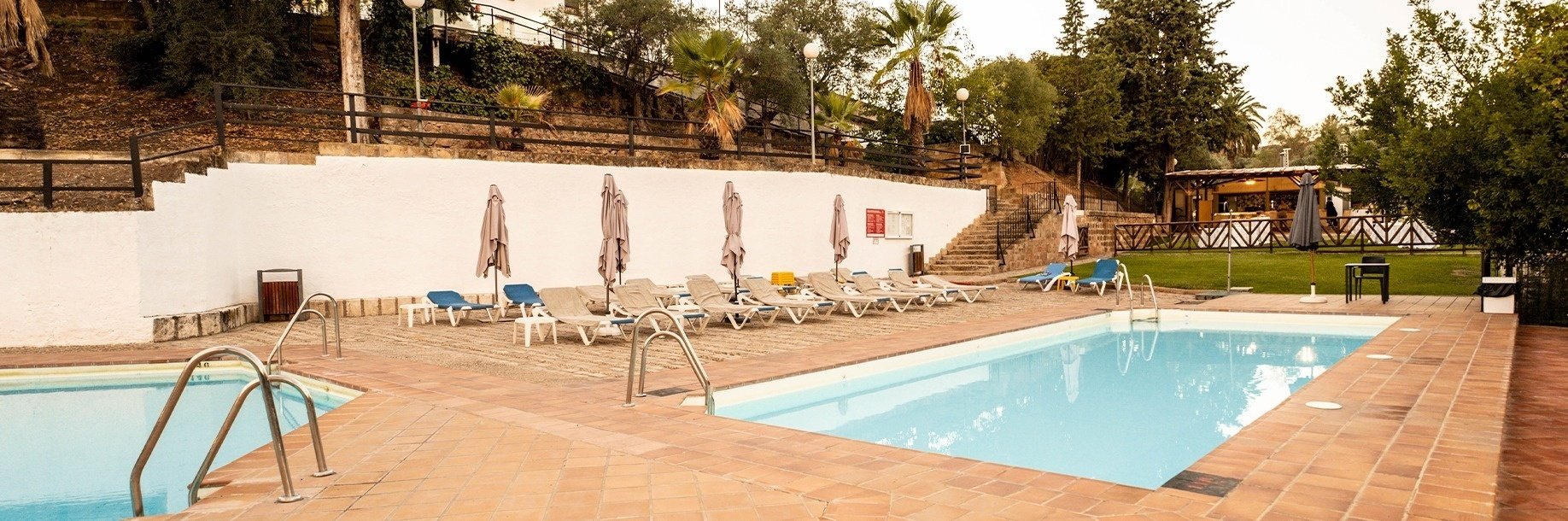 una piscina rodeada de sillas y sombrillas con escaleras que conducen a ella