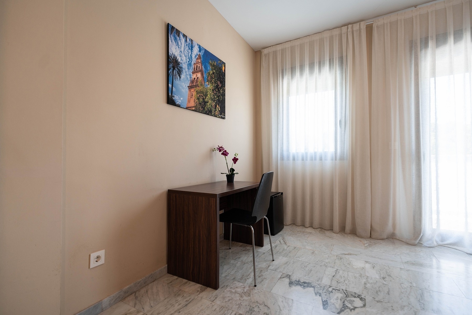 a picture of a tower hangs above a desk in a room