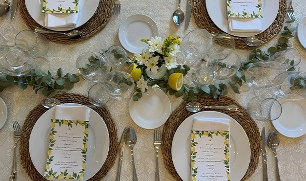 a table set with plates glasses and napkins with lemons on them