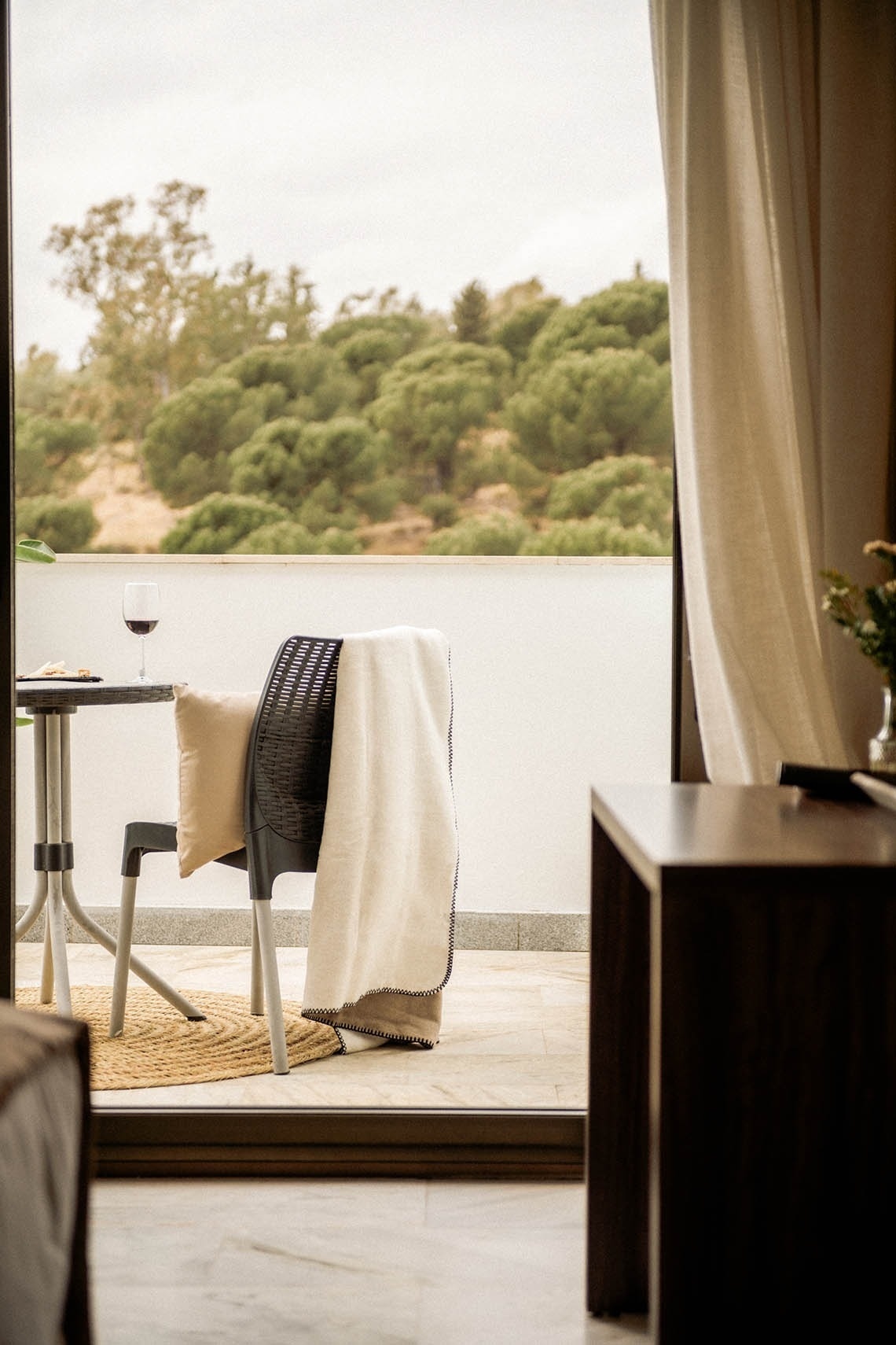 a balcony with a table and chairs and a glass of wine