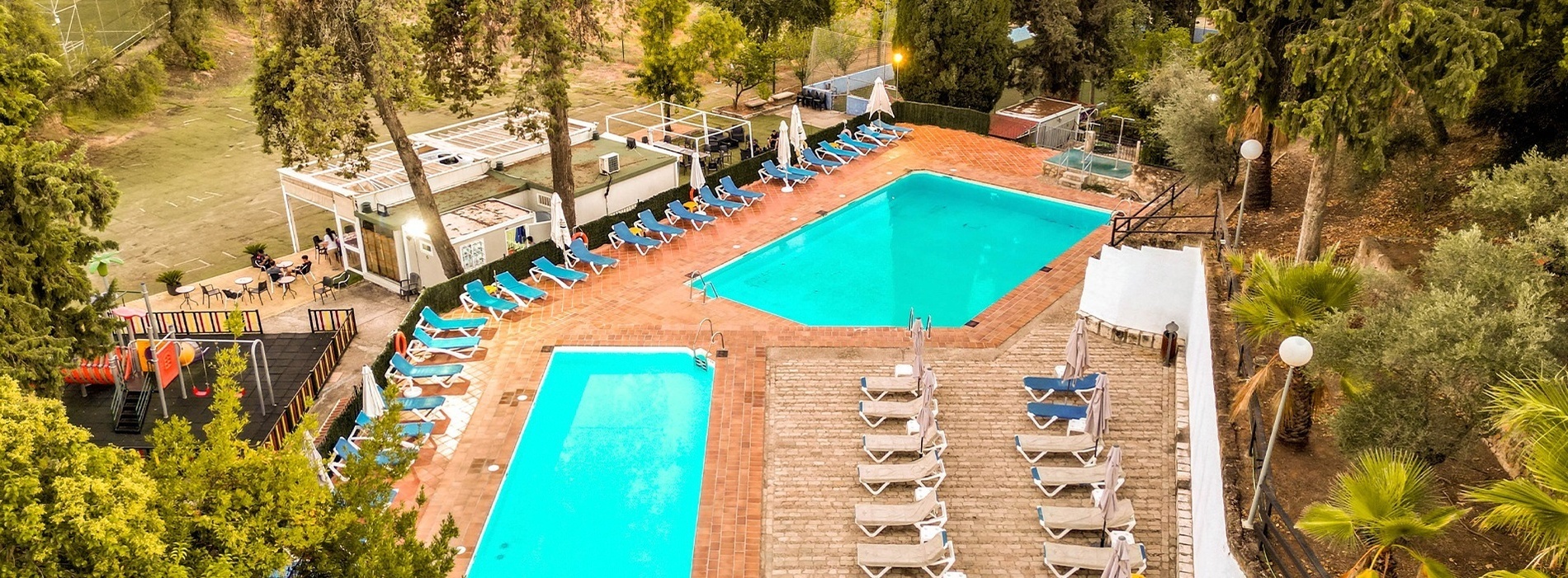 an aerial view of a large swimming pool surrounded by chairs and umbrellas
