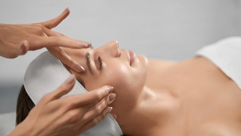 a woman is getting a facial massage with her eyes closed