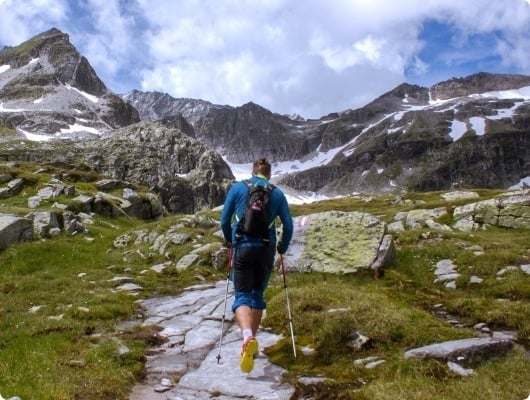 un hombre con una mochila camina por un sendero de montaña .