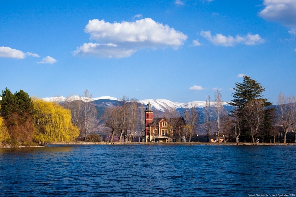 un edifici a la orilla d' un llac amb l' aigua i les montagnes al fons