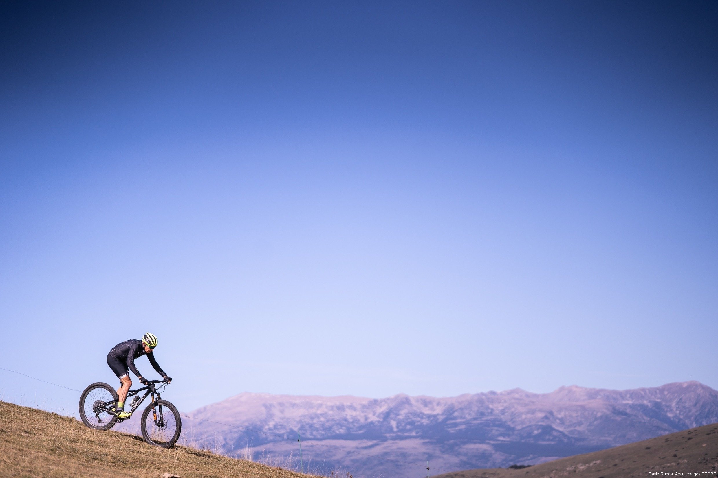 a person riding a bike on a hill with mountains in the background