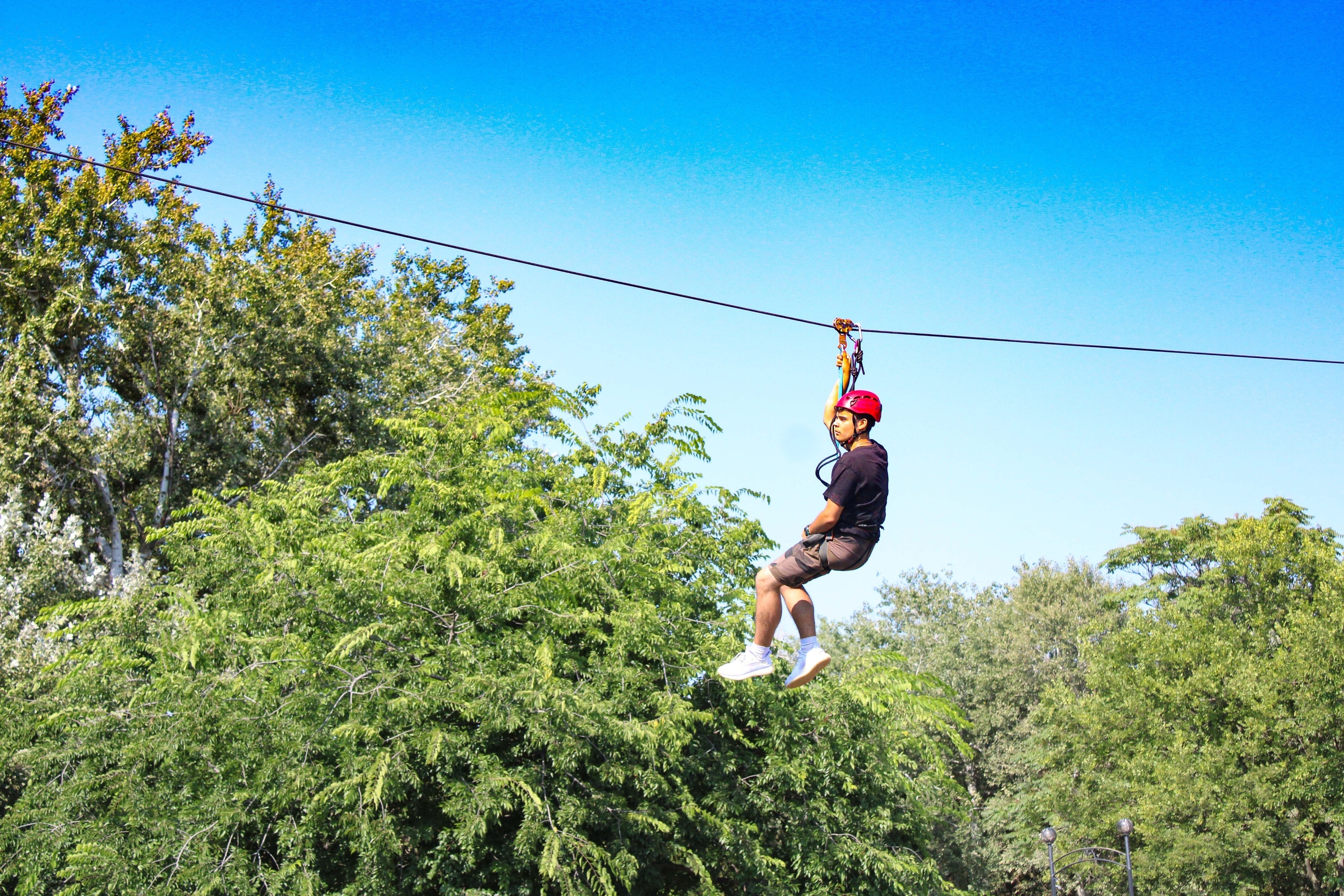 a man in a red helmet is flying through the air on a zip line