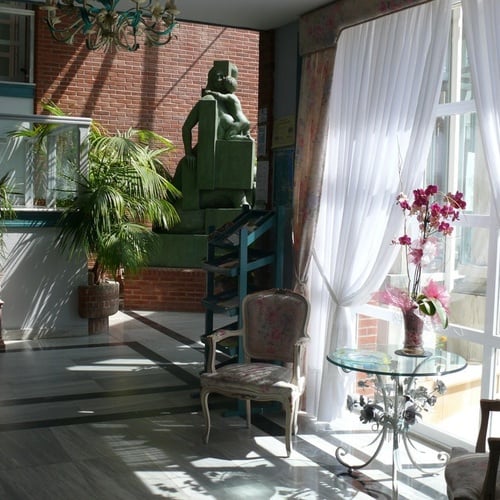 Elegant Torre Cristina lobby with statues and plants, natural light.
