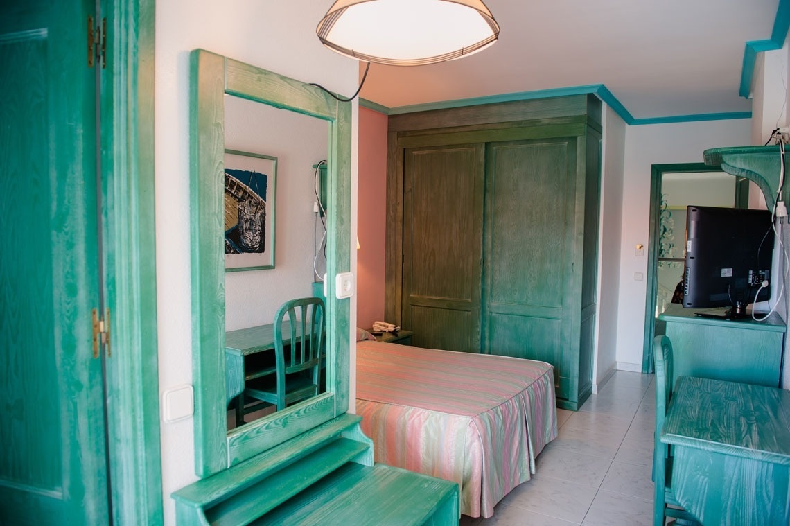 una habitación verde con una cama y un espejo