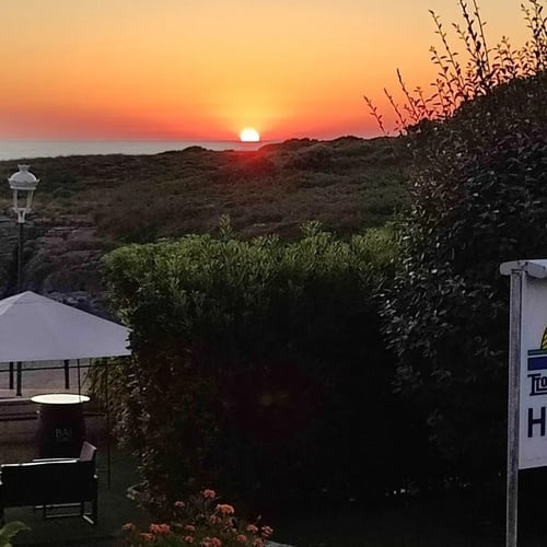 Torre Cristina Hotel at sunset, offering sea views and nature.