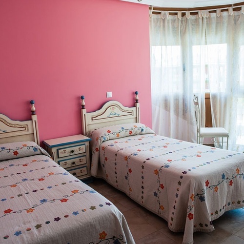 Twin room at Torre Cristina with single beds, floral duvets, and pink walls.