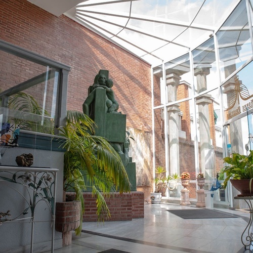 Torre Cristina lobby with sculpture, plants, and natural light.