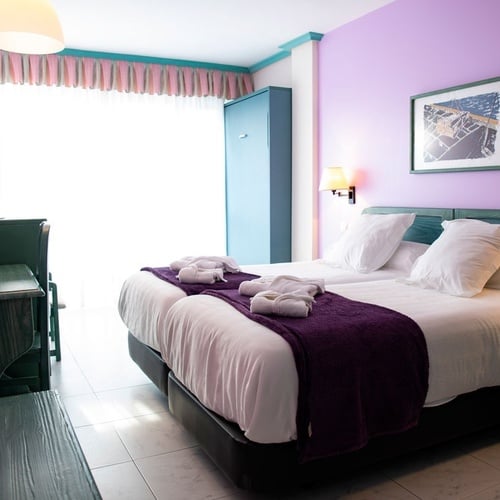 Double room with two beds, purple throw, and art at Torre Cristina.