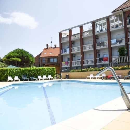 Crystal clear pool at Torre Cristina with sun loungers and apartment building.