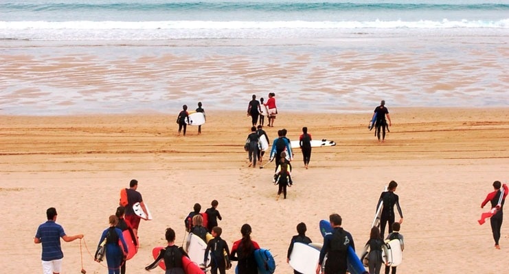 un grupo de surfistas camina por la playa con sus tablas de surf
